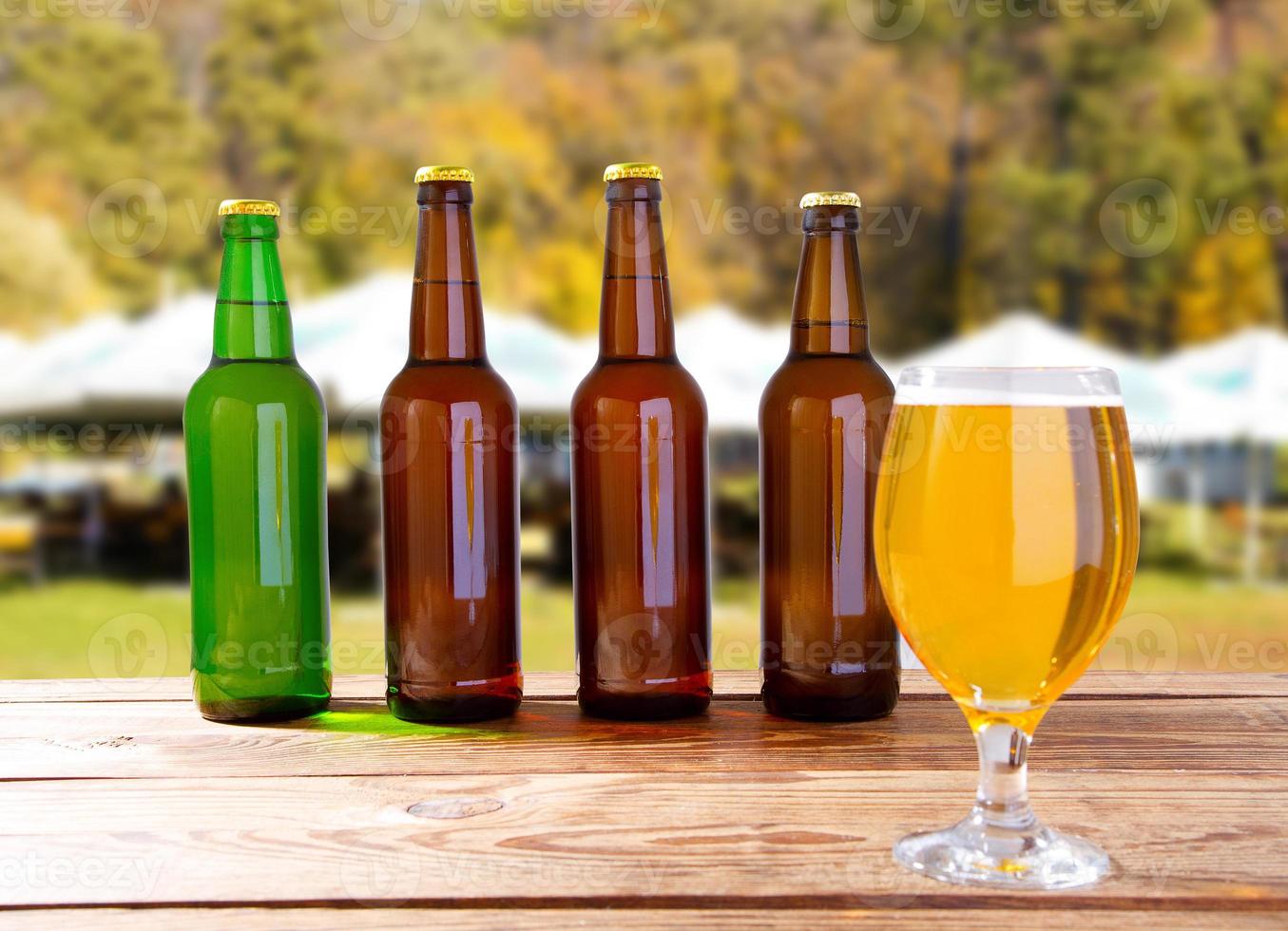 beer bottles and beer goblet on blurred background of summer playground photo