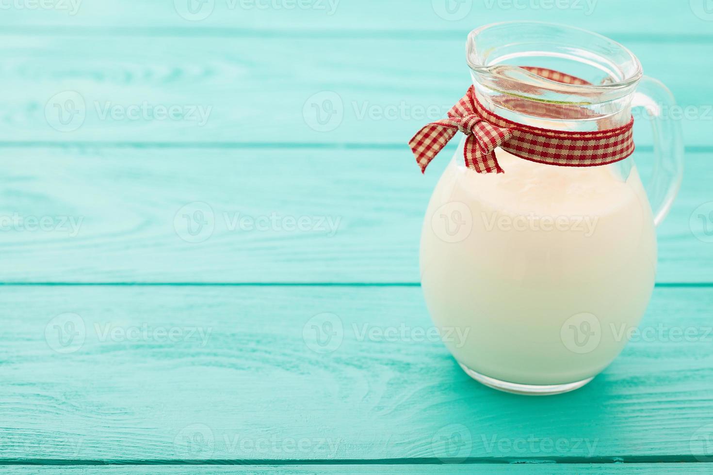 Jug of milk on blue wooden background. Selective focus photo