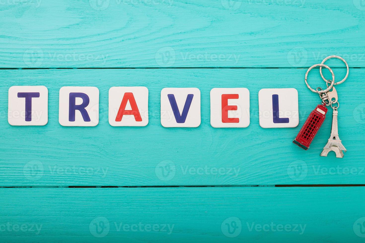 Tourism concept. Word travel with trinket on blue wooden background. Copy space. Top view. Mock up photo
