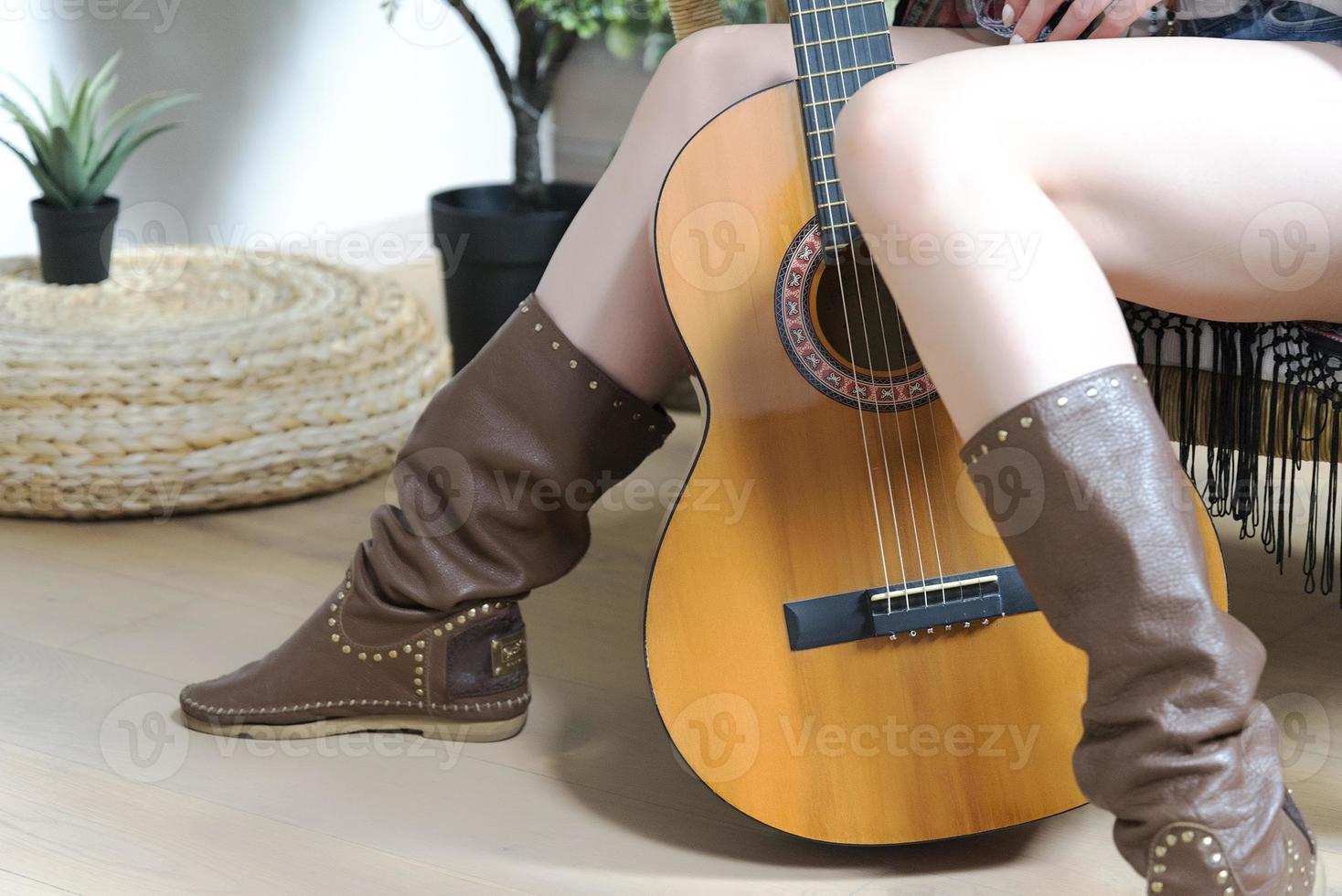 Legs in leather cowboy boots and a seven-string guitar. photo