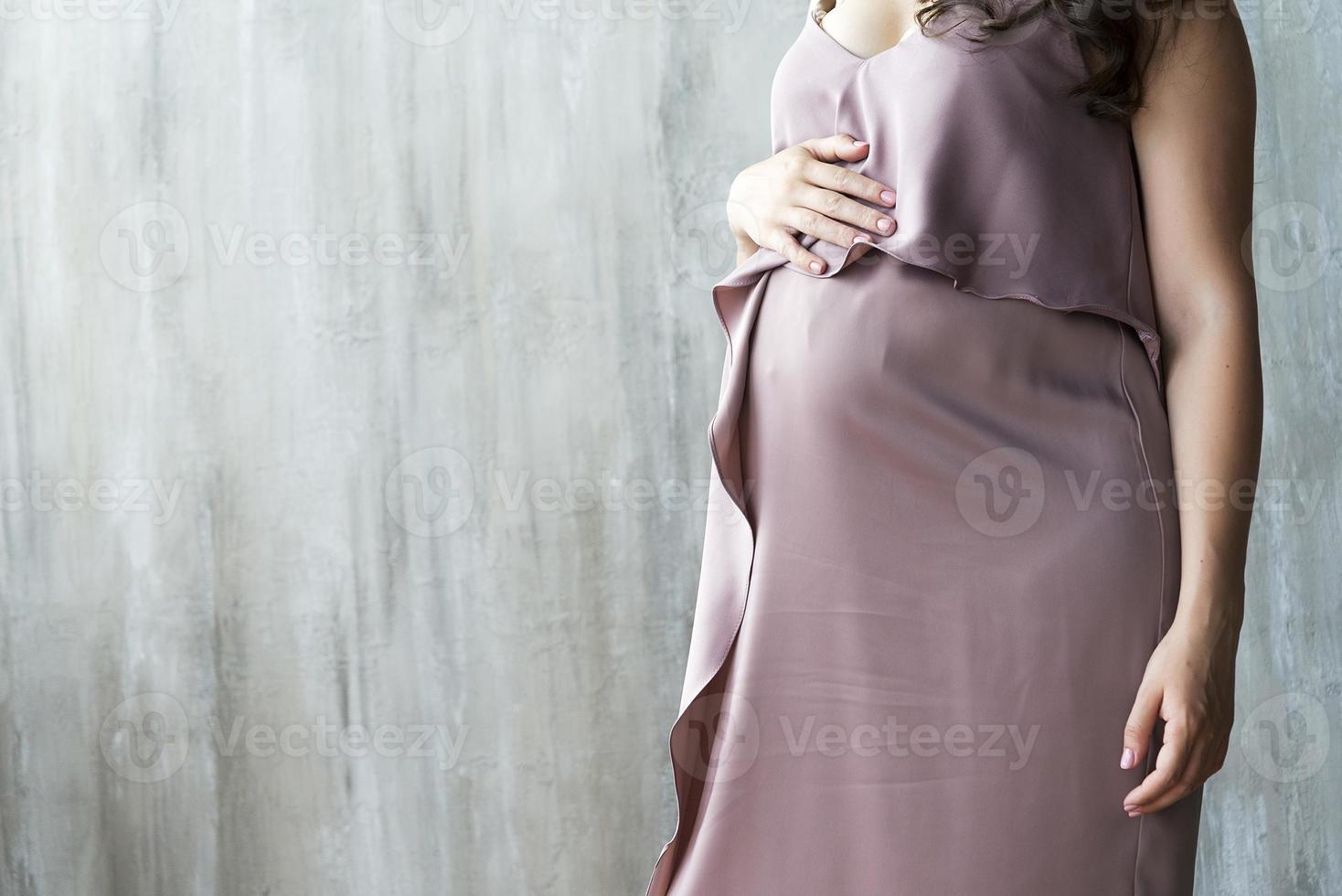 The abdomen of a pregnant woman on gray background. photo