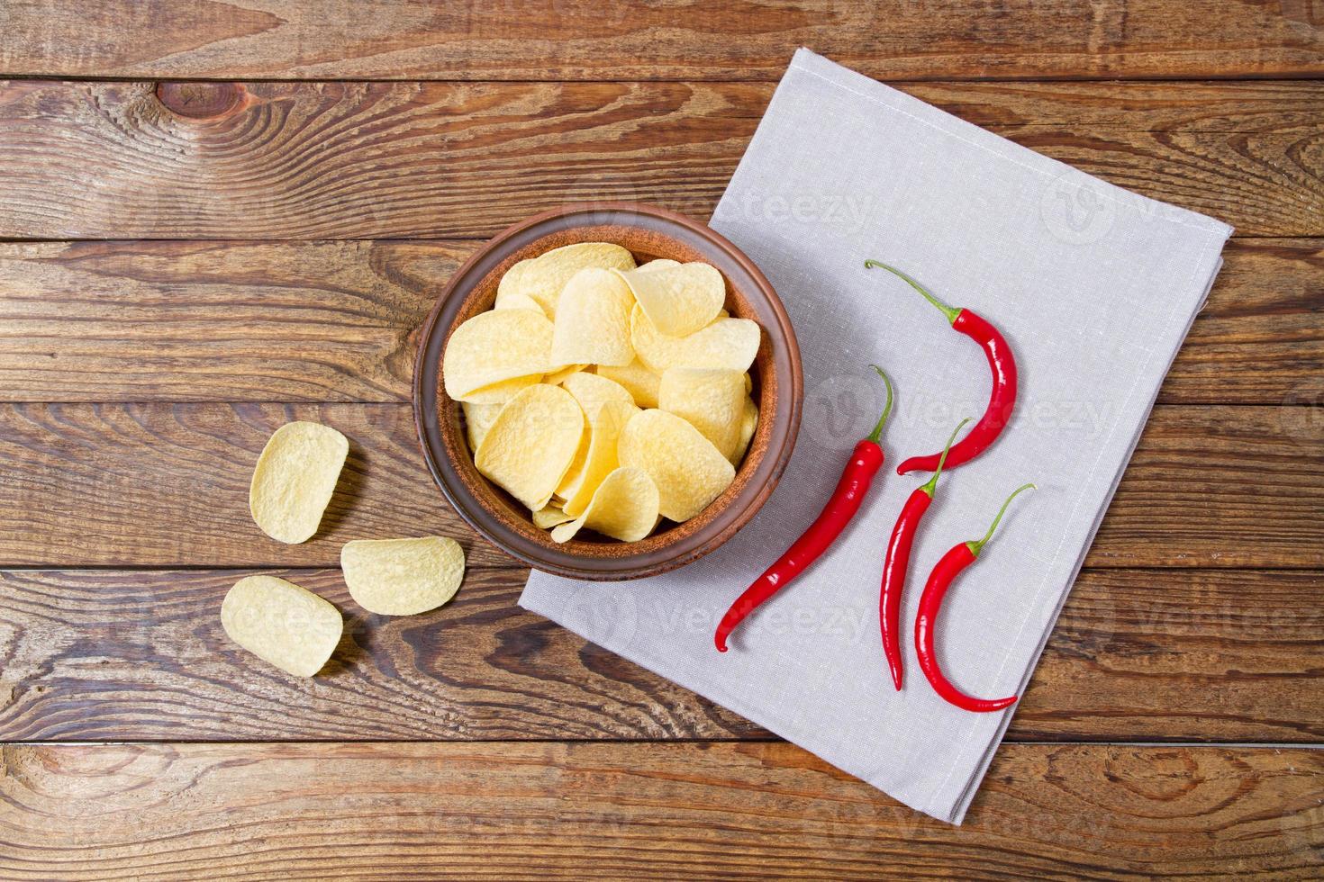 top view potato chips and red chili peper on wooden table,tablecloth photo
