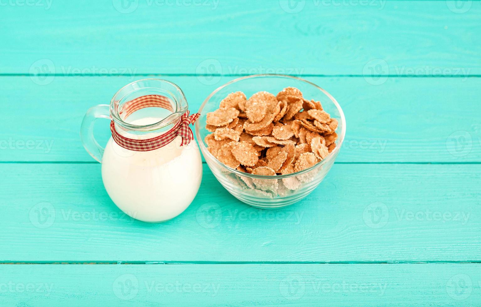 Food concept. Oat flakes and jug of milk on blue wooden background. Top view and copy space. Mock up photo