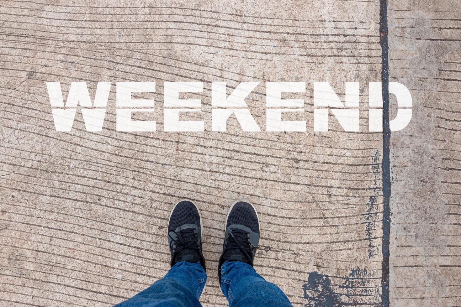 A weekend concept, a man wears black shoes on a concrete pavement with WEEKEND letters. photo