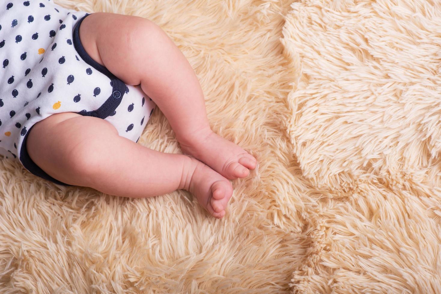 Bare legs of a newborn on a fluffy, light, one-ton, warm covering. Cute newborn baby feet close up photo