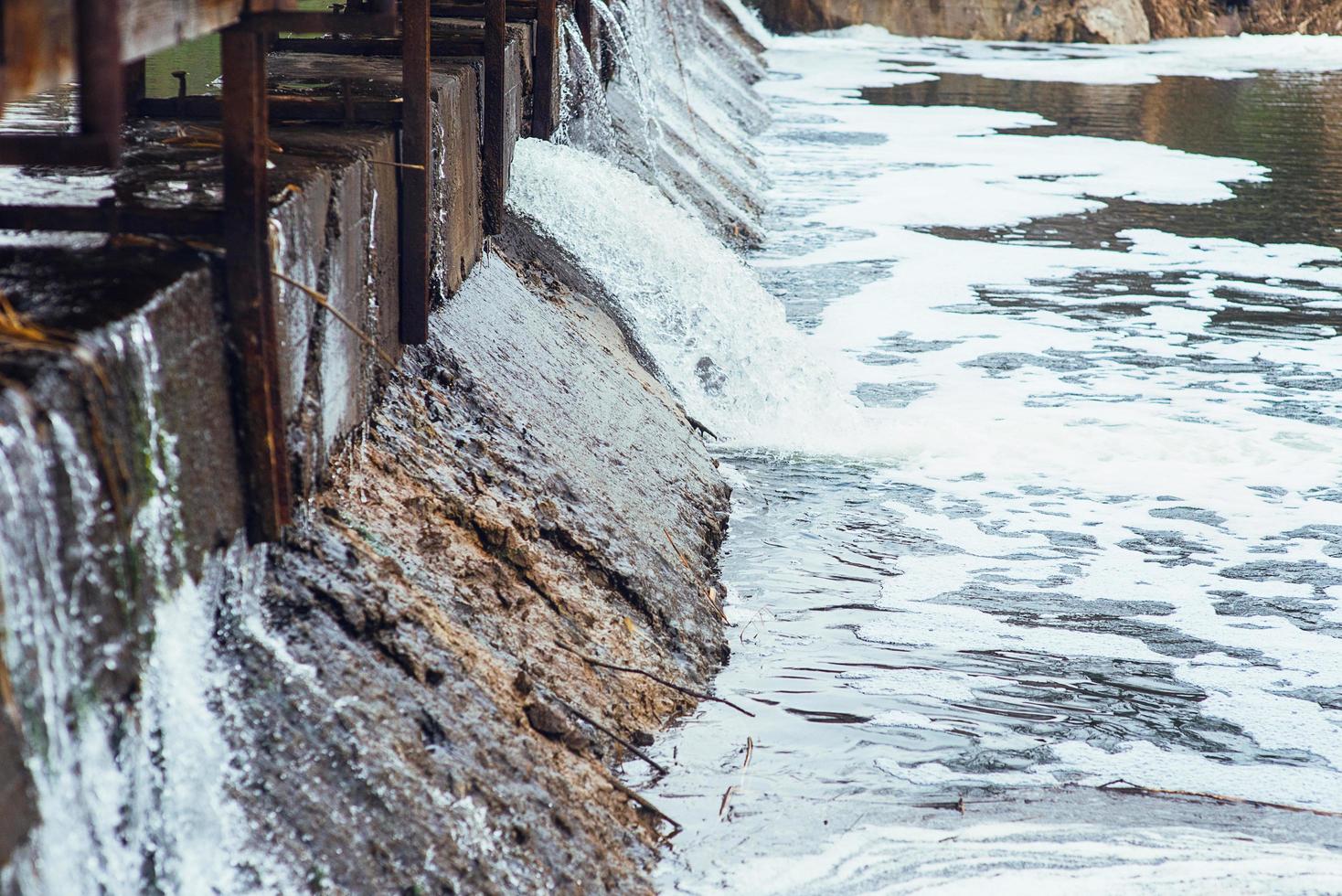 el agua fluye rápidamente en cascada a lo largo de la pared de hormigón de la presa. presa. foto