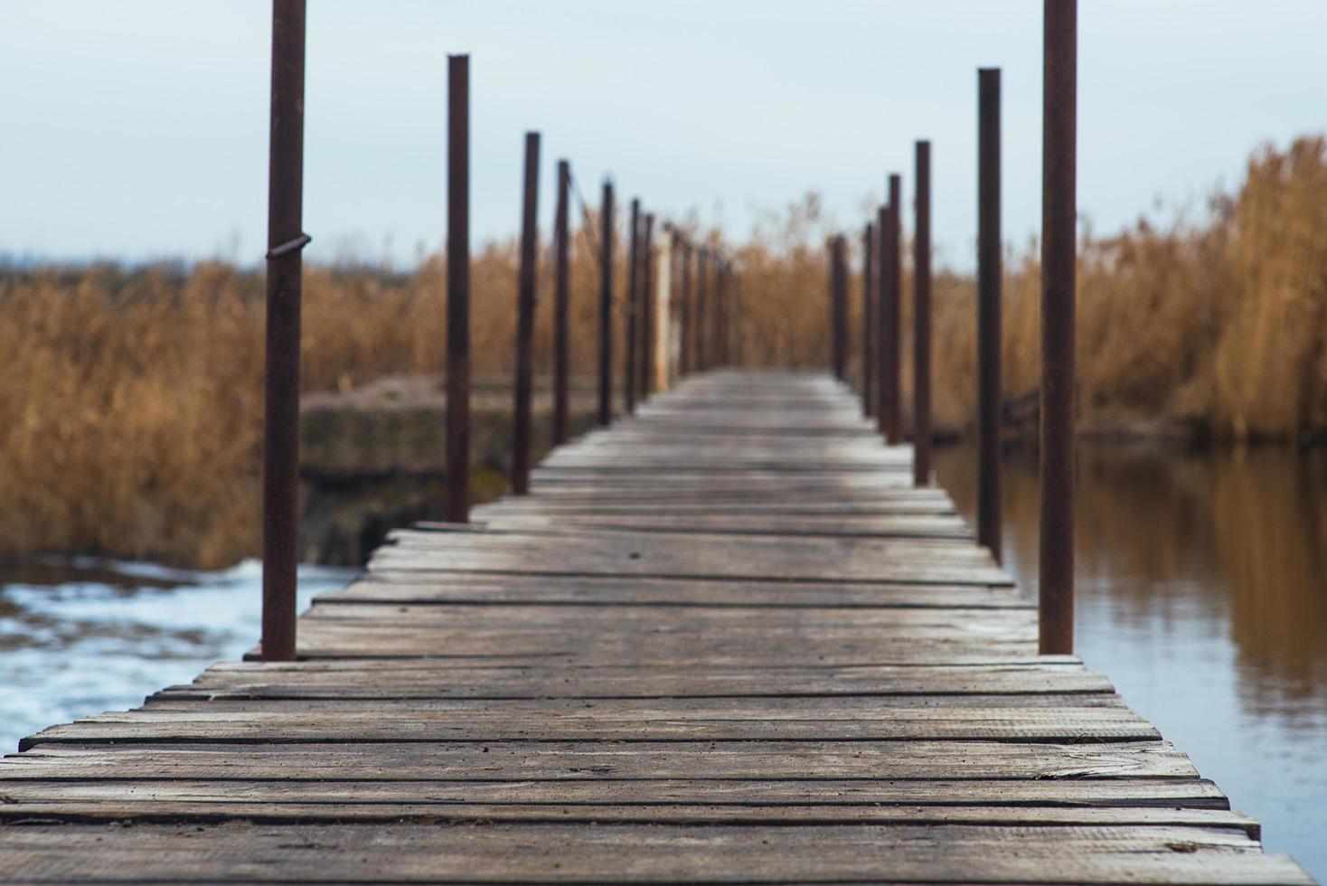 puente de madera húmedo sobre el río. cruce de río improvisado foto