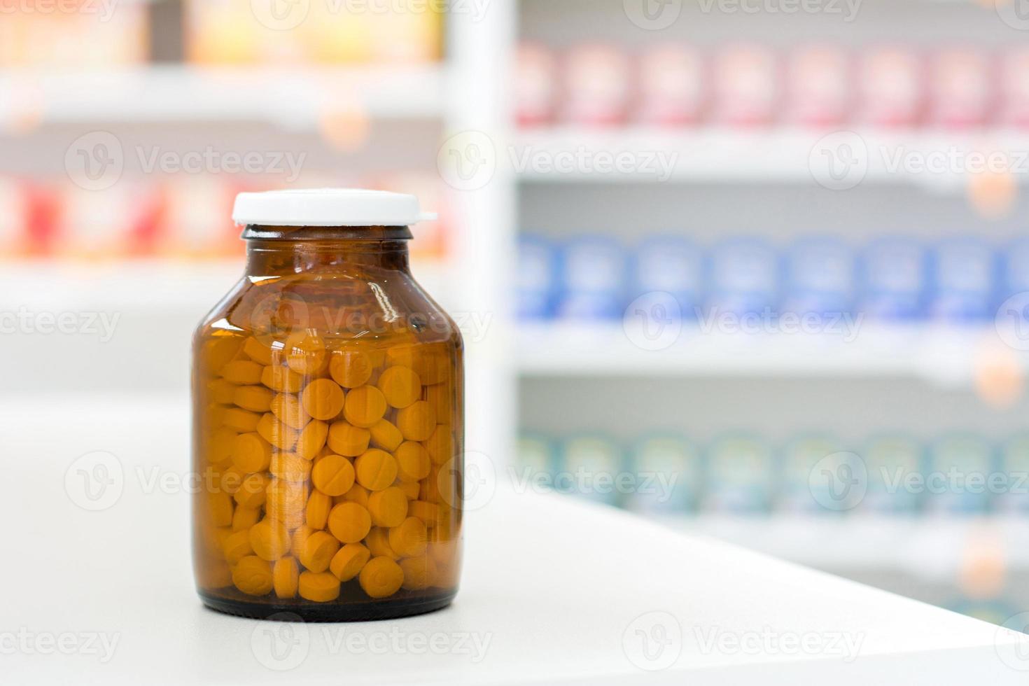 Píldoras pequeñas en frasco transparente de medicina ámbar en la mesa de la farmacia foto