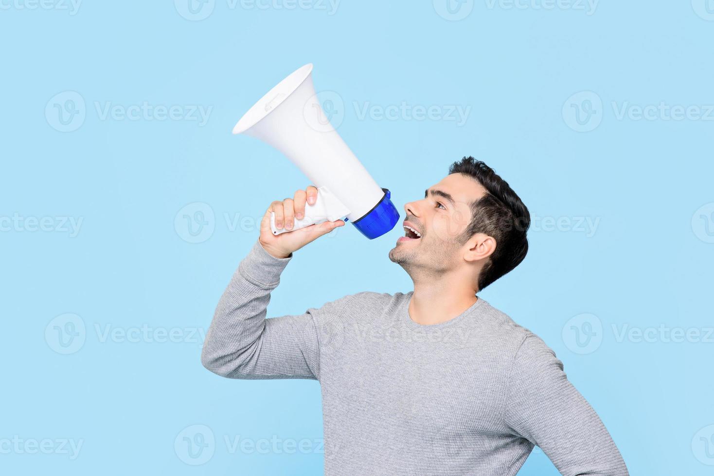 Caucasian man shouting on megaphone isolated on light blue background photo