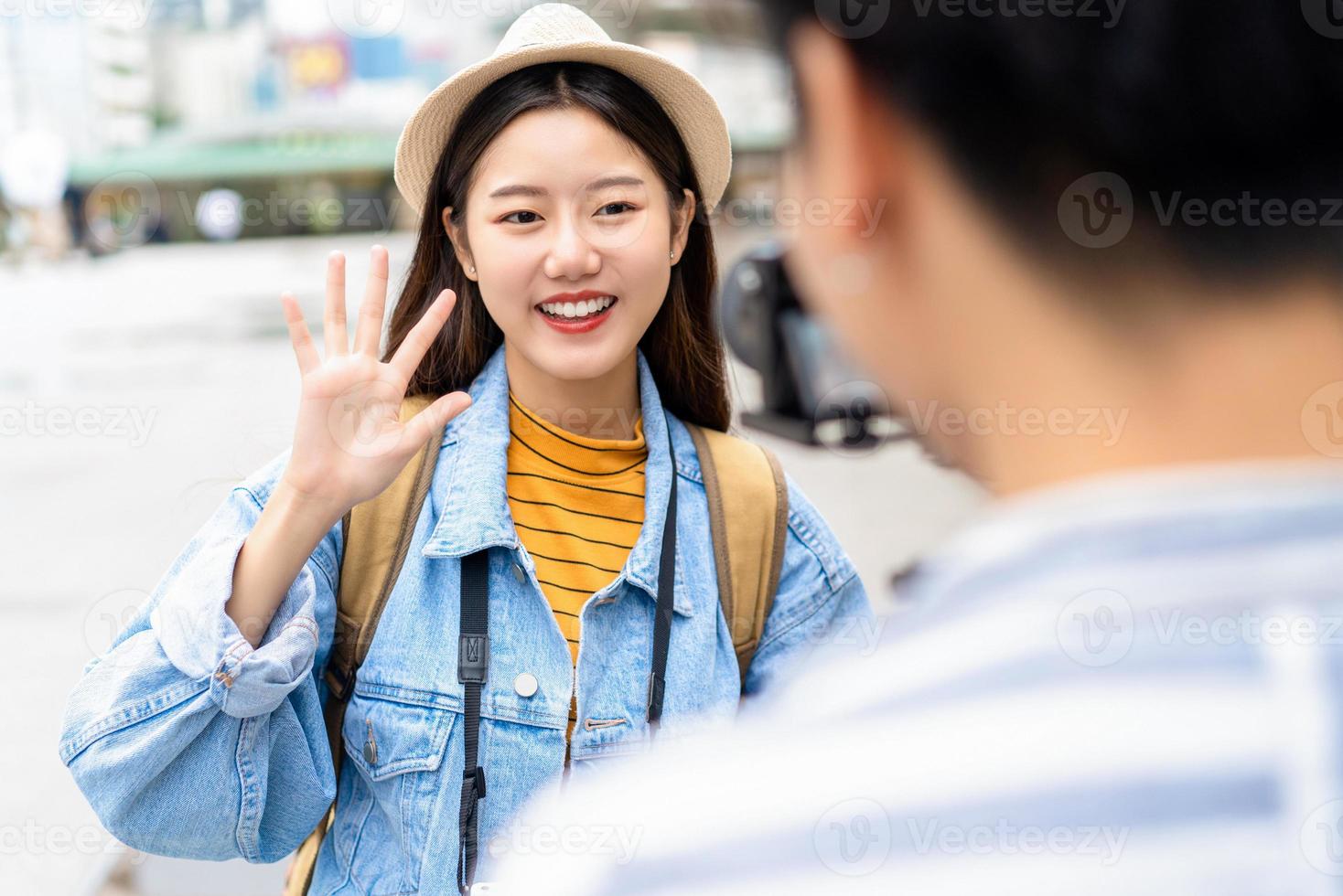 Smiling beautiful Asian woman tourist travel vlogger say hi to camera in the city photo