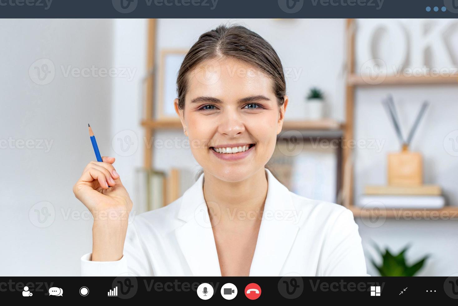 mujer caucásica sonriente con traje formal de negocios mirando la cámara mientras hace videollamadas, trabaja desde casa y conceptos de entrevistas en línea foto