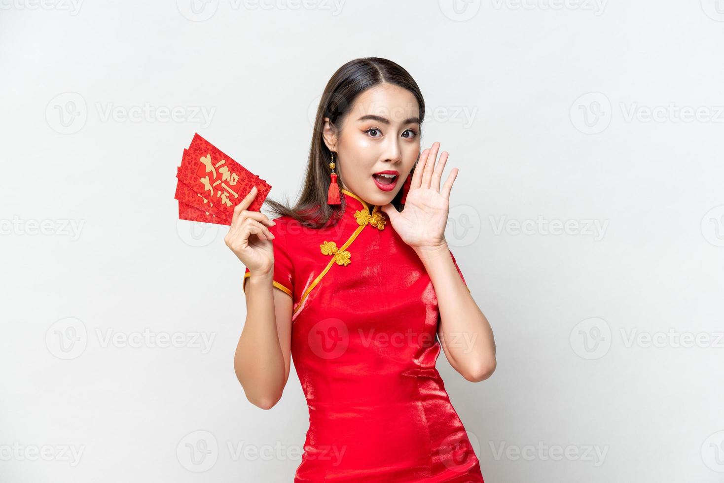Surprised Asian woman in traditional oriental costume holding red envelopes or Ang Pao in gray isolated background, Chinese text means great luck great profit photo