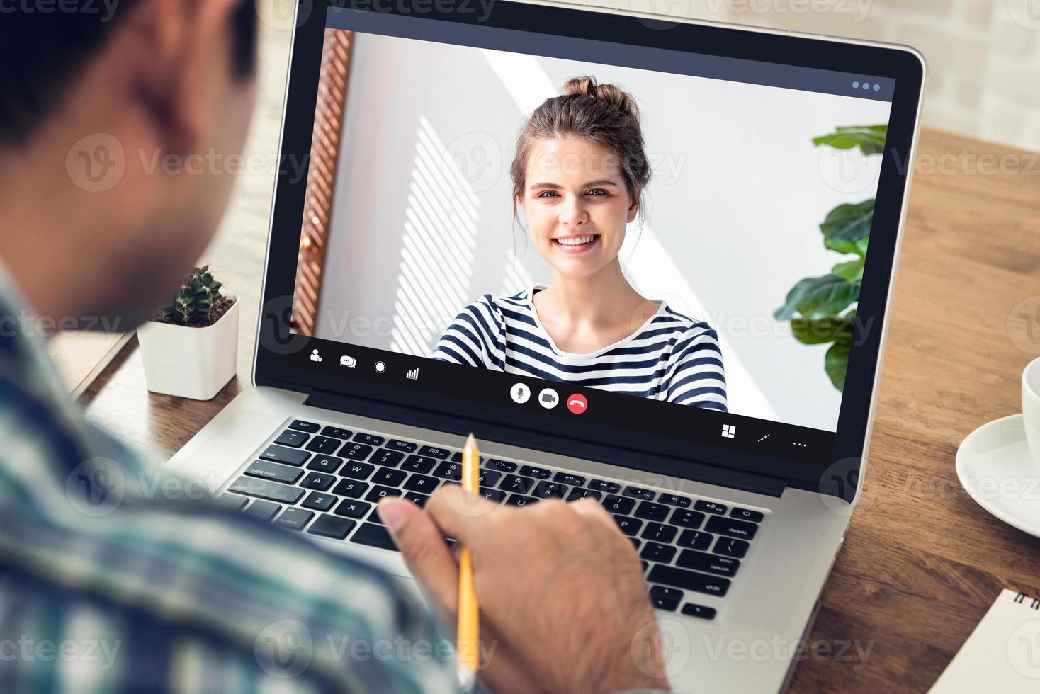 Young man learning foreign language with Caucasian woman via online video call meeting on laptop in the time of pandemic photo