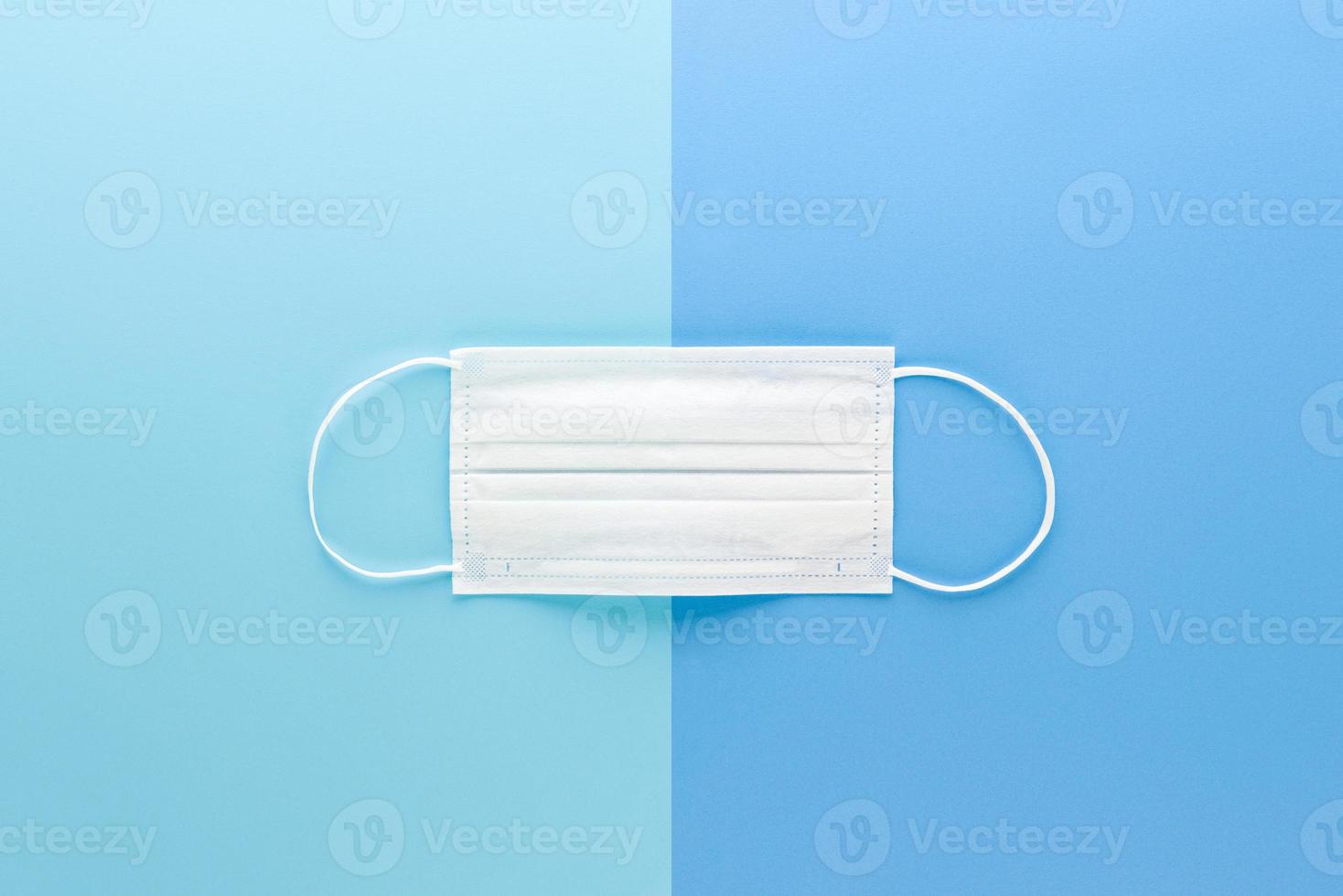 New clean white medical face mask isolated on light blue paper backgrounds top view photo