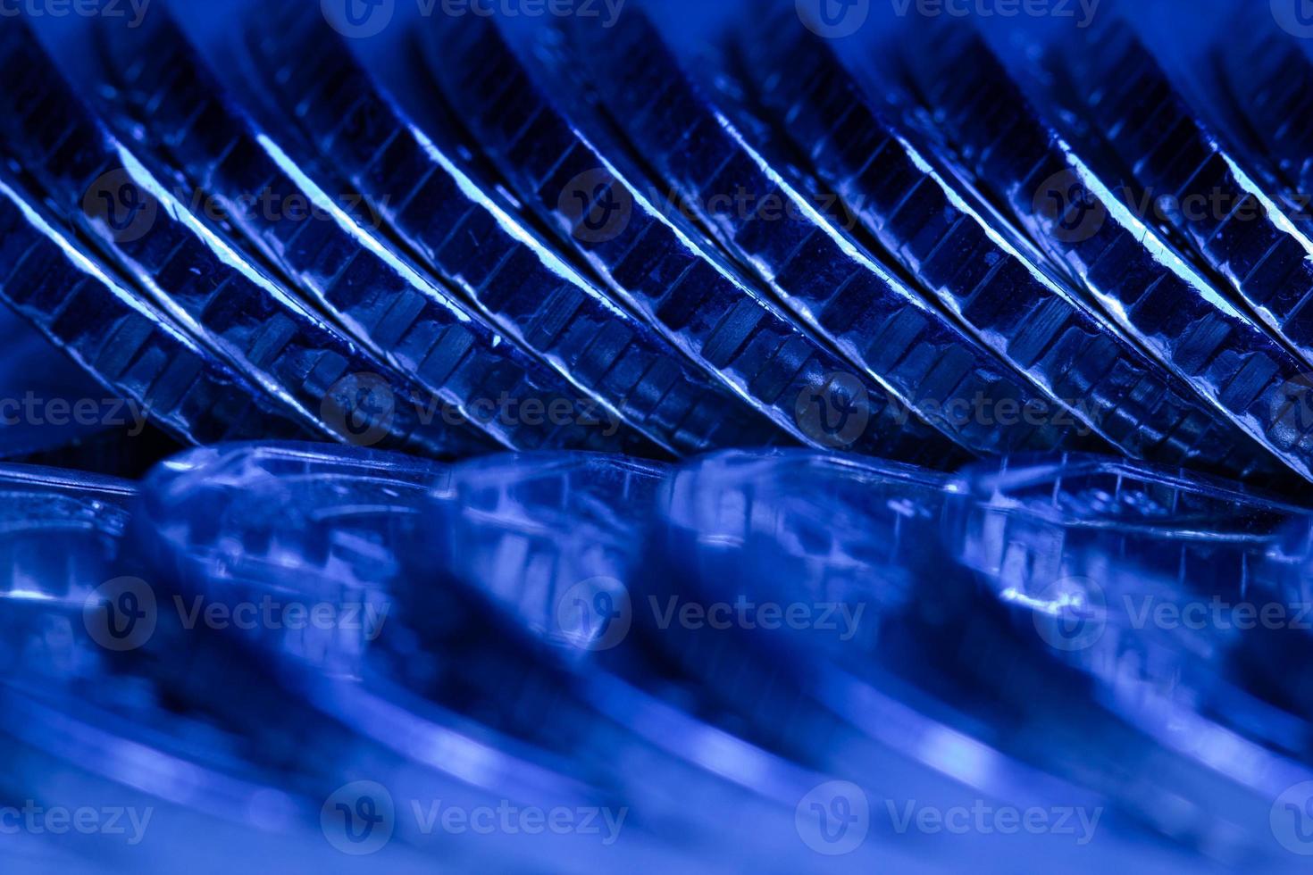 Lots of metal coins in a row in dark blue light. Beautiful money background. Coins background. Financial concept. Copy space for text. Close-up photo