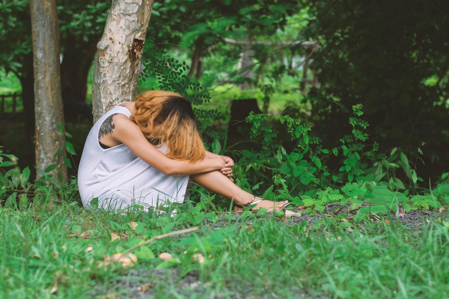 young hipster woman, sad, long-haired  sitting hugging legs. photo