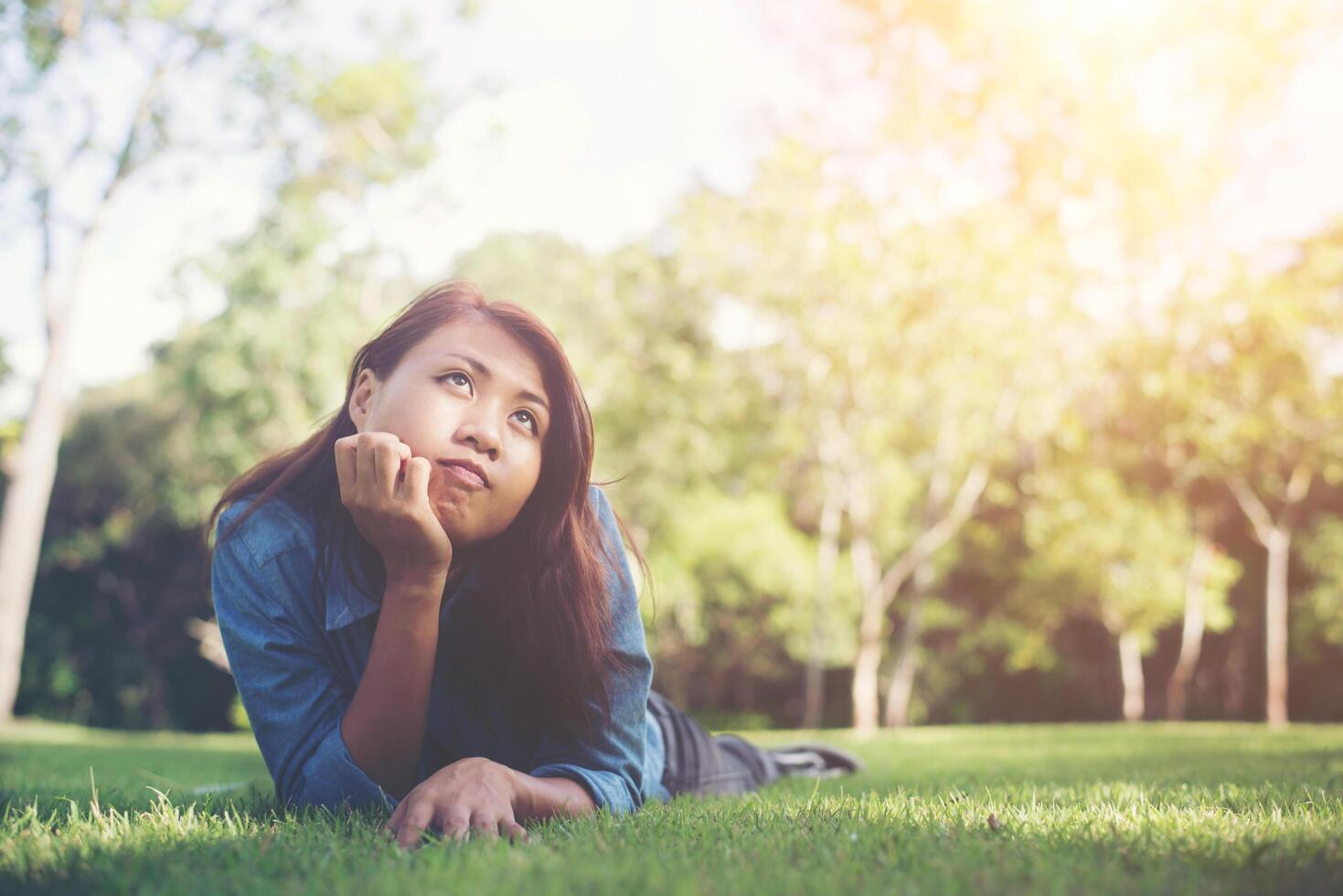 encantadora mujer hipster joven y sonriente tumbada en la hierba verde. foto