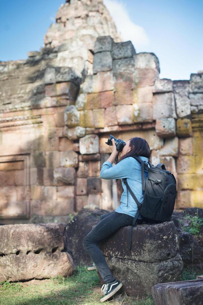 Young attractive woman photographer tourist with backpack coming to shoot photo at ancient phanom rung temple in thailand.