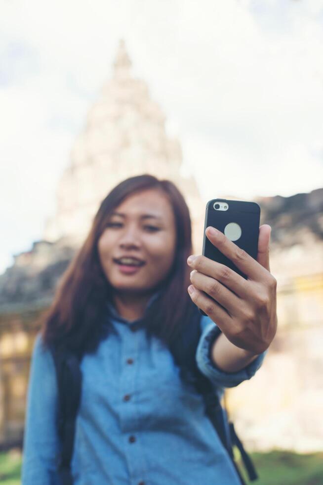 joven mujer atractiva tomando selfie en su teléfono mientras viaja en el templo de phnom peldaño en tailandia. foto