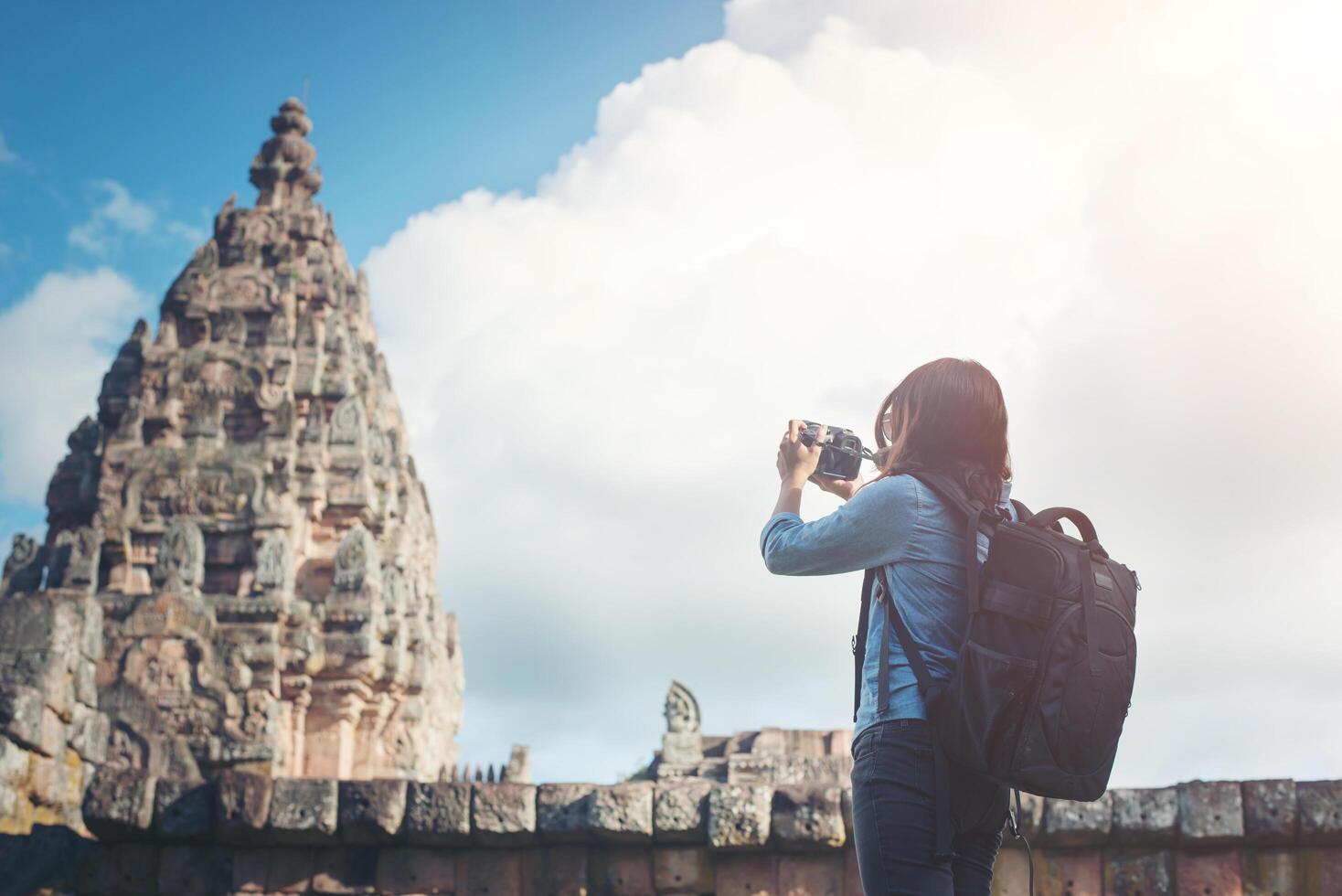 Young attractive woman photographer tourist with backpack coming to shoot photo at ancient phanom rung temple in thailand.