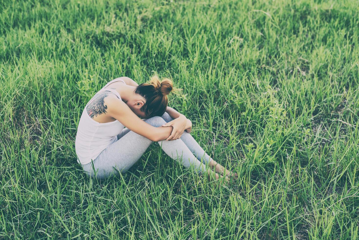 Woman life concept  sad woman hug her knee and cry in meadows. photo