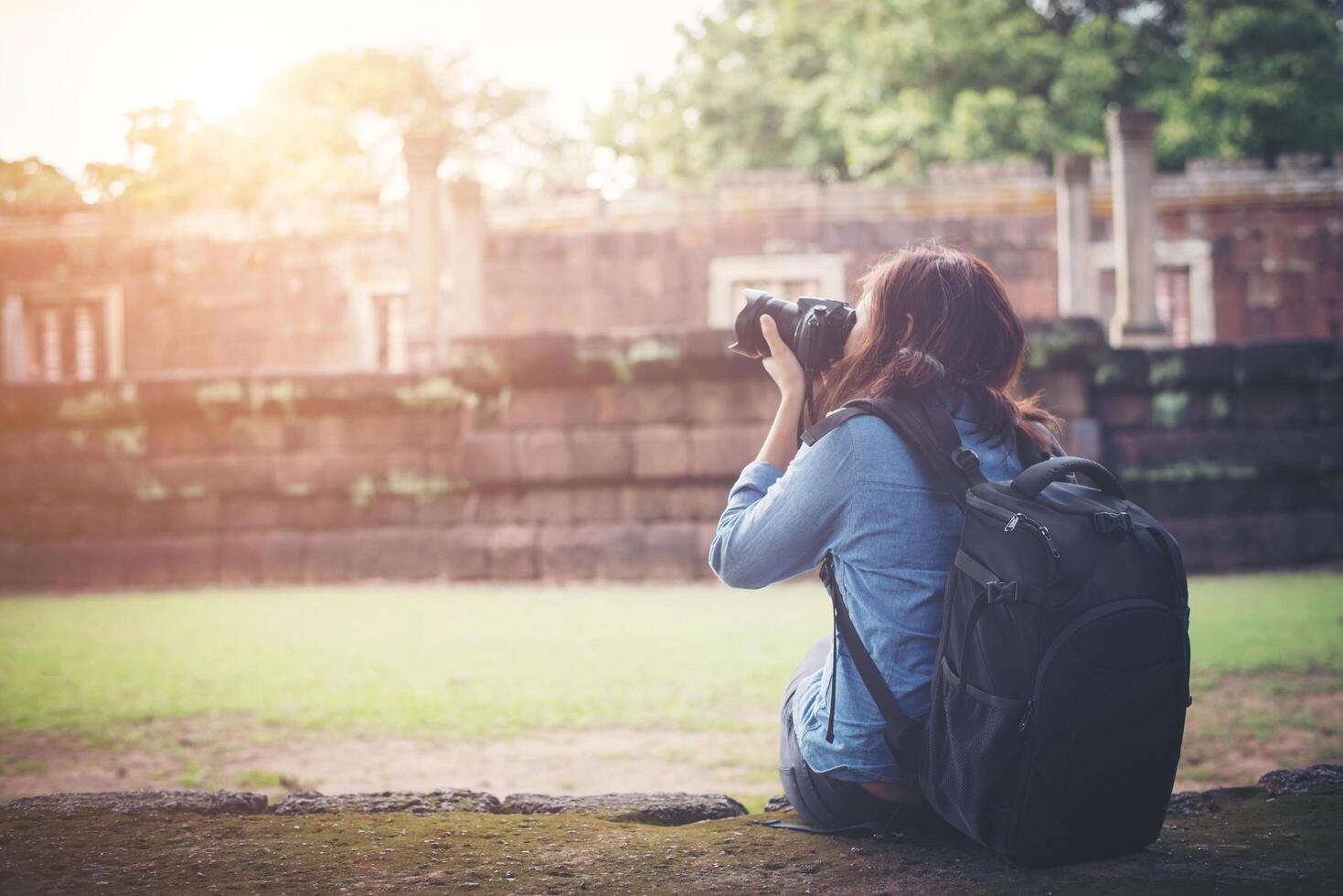 Young attractive woman photographer tourist with backpack coming to shoot photo at ancient phanom rung temple in thailand.