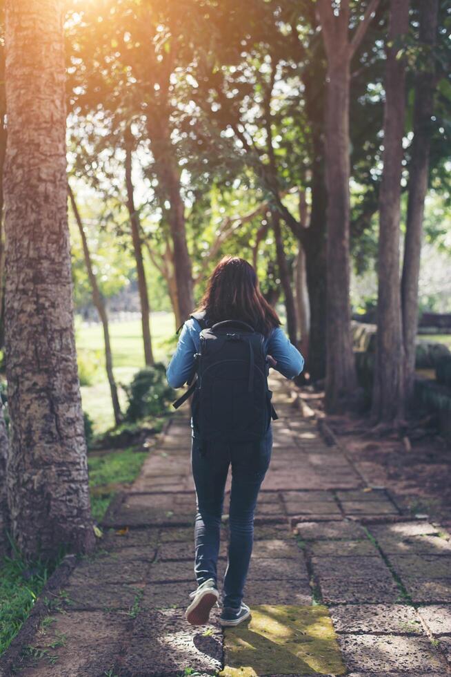 mujer joven hipster con mochila caminando en el bosque, vista trasera. foto
