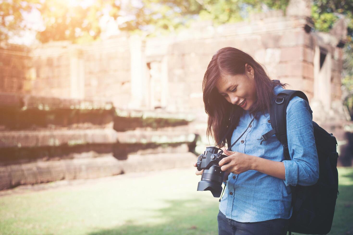 Young attractive woman photographer tourist with backpack coming to shoot photo at ancient phanom rung temple in thailand.