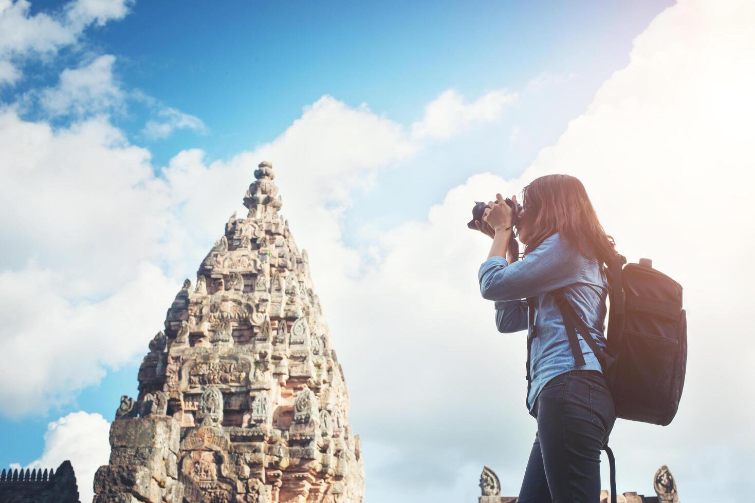 Young attractive woman photographer tourist with backpack coming to shoot photo at ancient phanom rung temple in thailand.