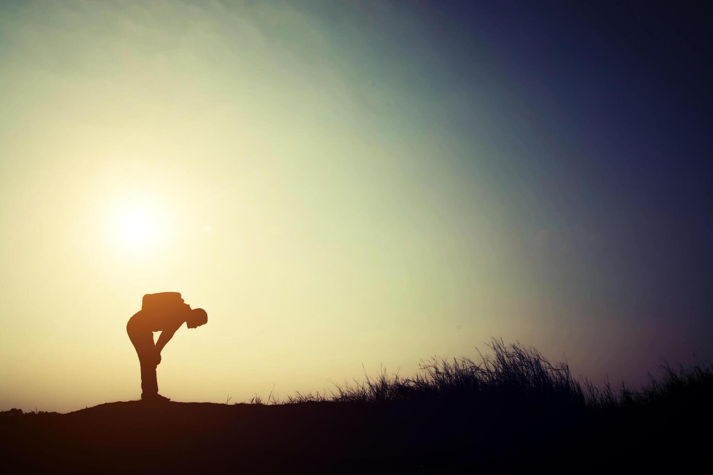 Silhouette of young man tired for walking alone with his backpack. photo