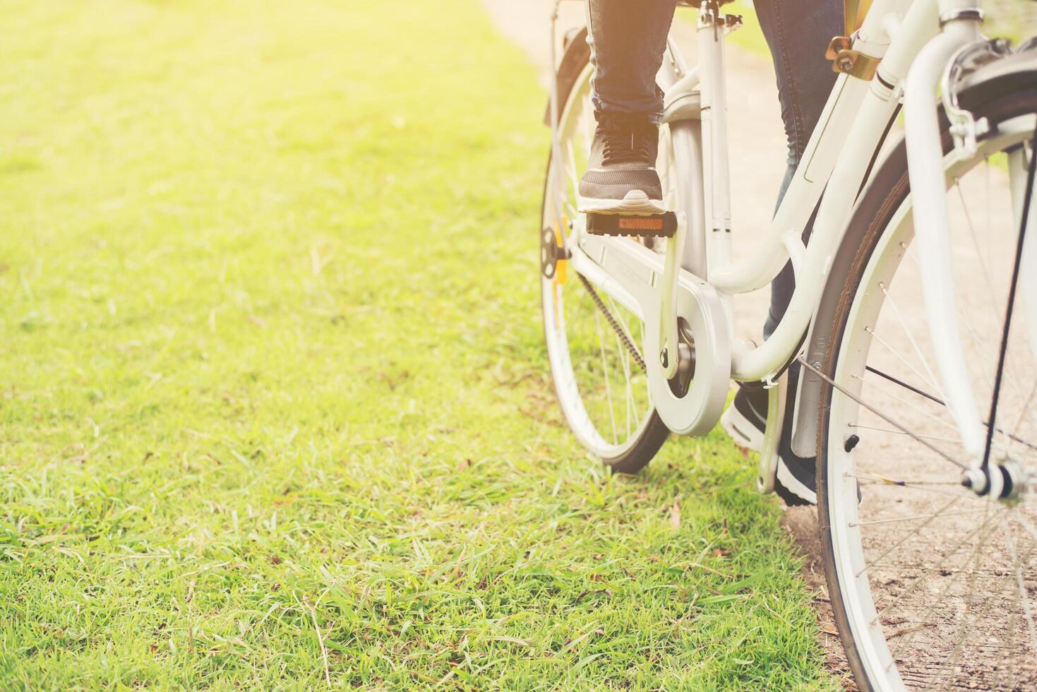 Close-up of young hipster woman holding her foot on bicycle pedal. photo