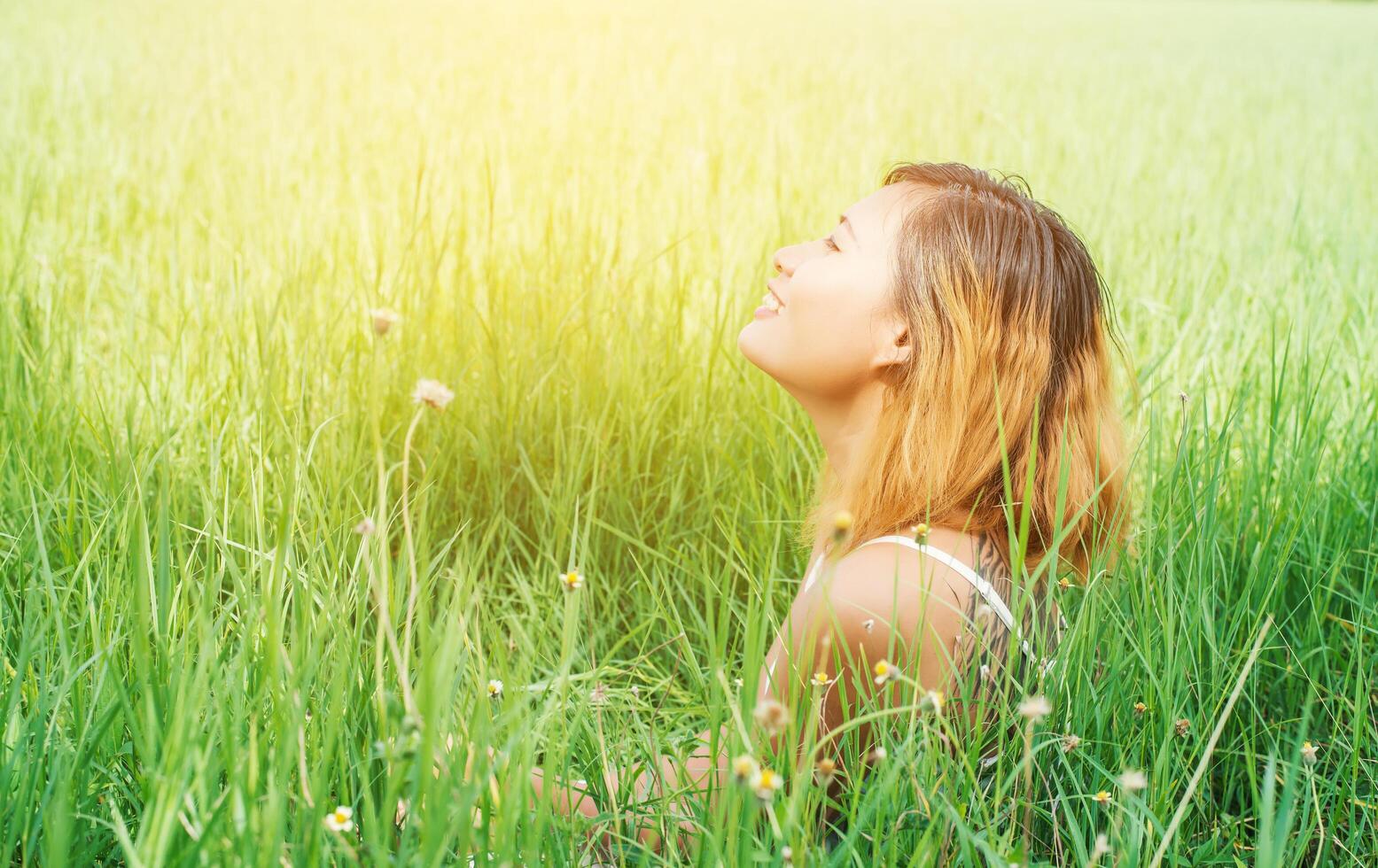 young beautiful woman sitting on grassland enjoy nature and fresh air happy. photo
