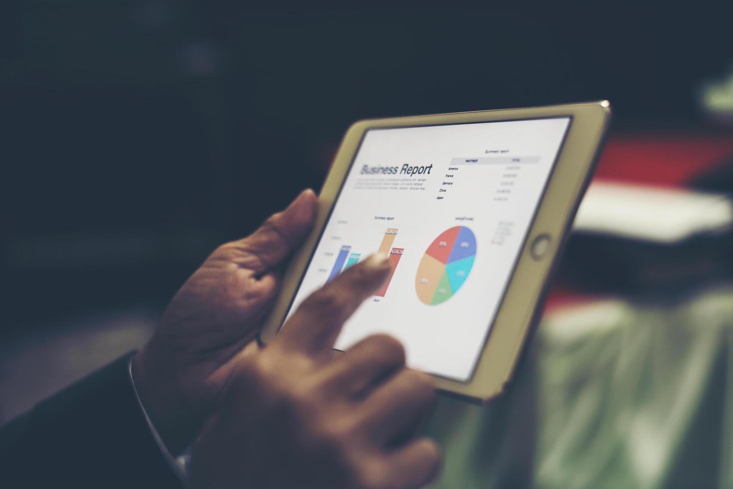 Business person hand holding financial statistics displayed on the tablet screen at office. photo
