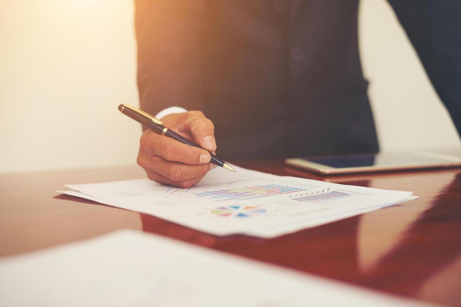 Woman's hand with a pen writing on the business paper. Report chart,busy at work. photo