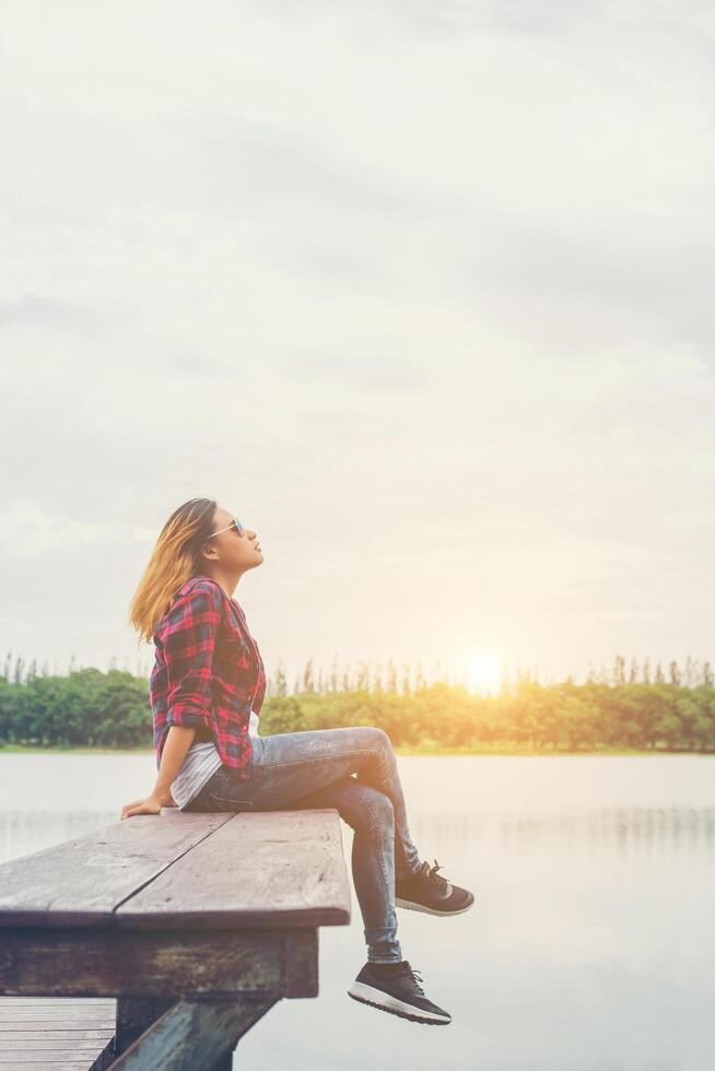 joven hermosa mujer hipster sentada en el muelle del lago, ambiente relajado, verano. foto