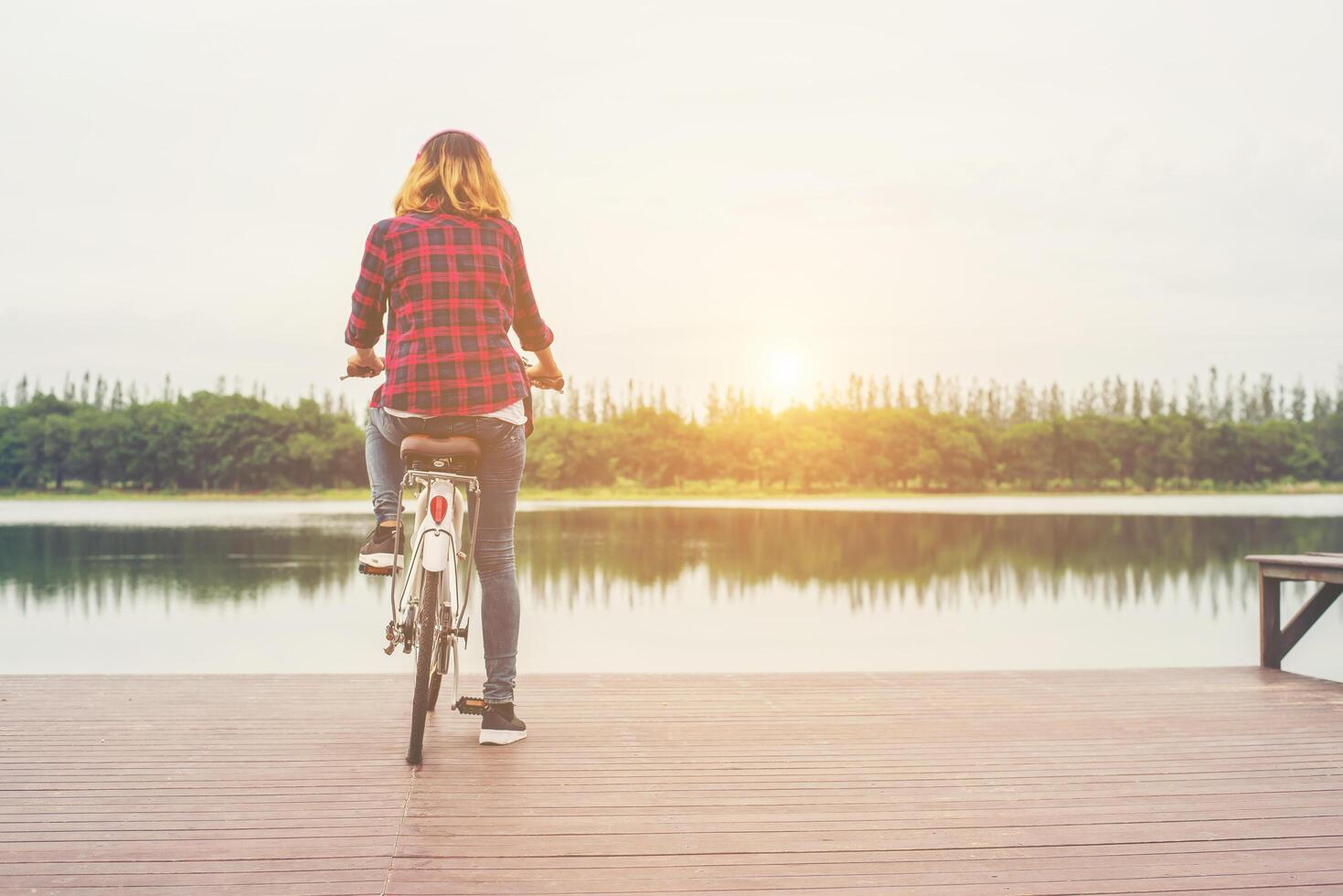 parte trasera de una joven hipster en bicicleta en un muelle, relajándose y disfrutando de las vacaciones de verano. foto