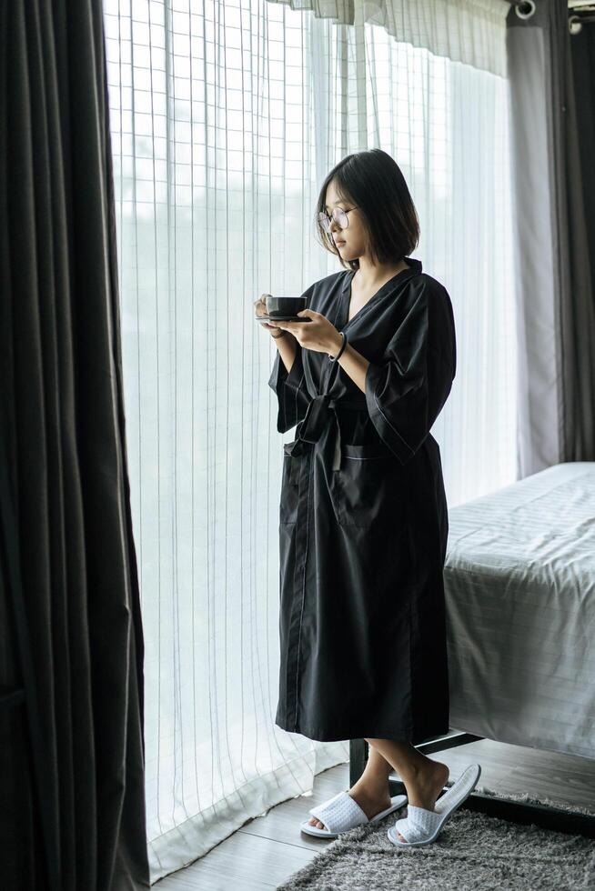 Women wearing black robes, handing coffee in the bedroom. photo