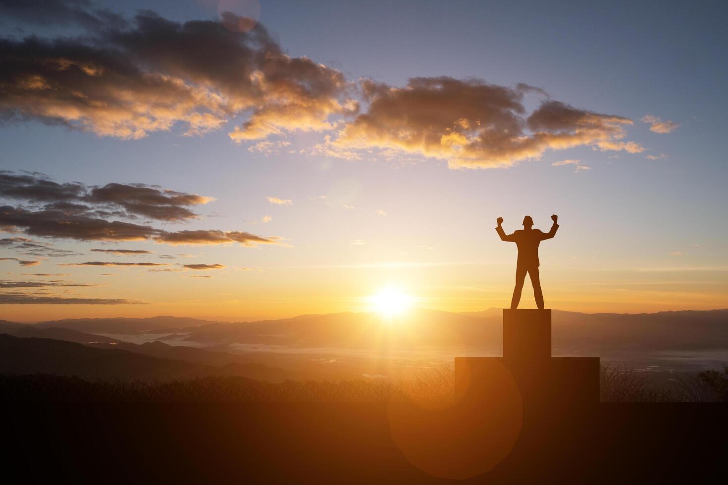 silueta de hombre exitoso en la cima de la colina y la puesta de sol foto