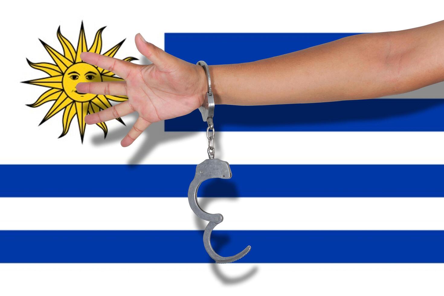 handcuffs with hand on Uruguay flag photo
