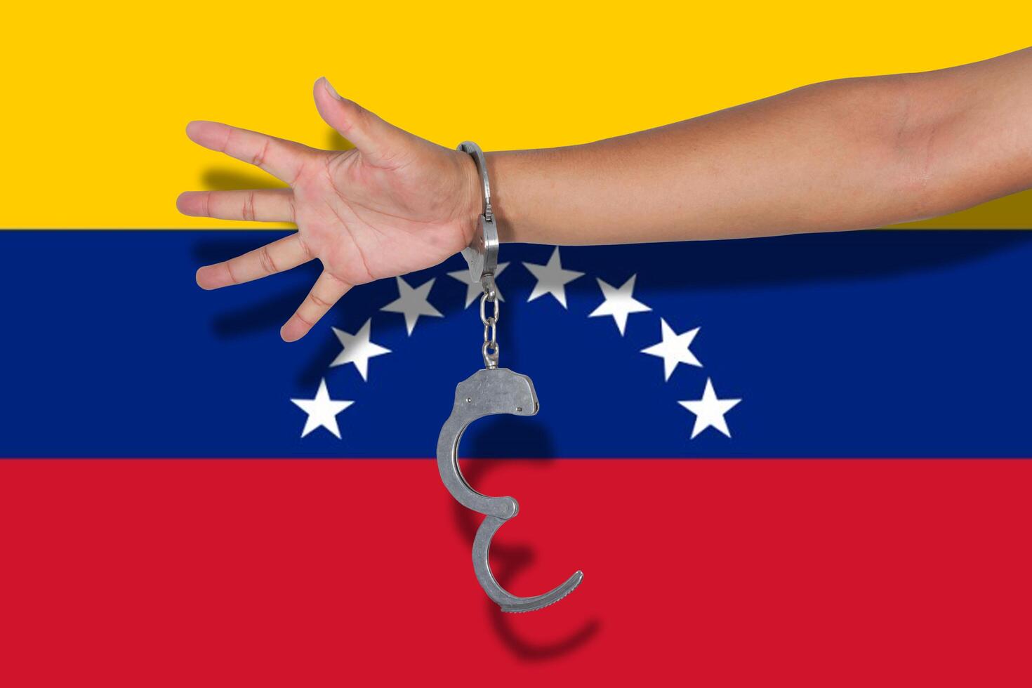 handcuffs with hand on Venezuela flag photo