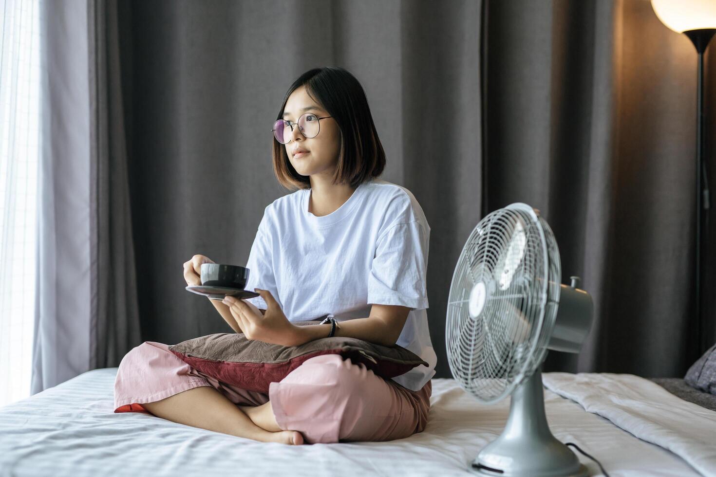 A girl sitting and drinking coffee on the bedroom. photo