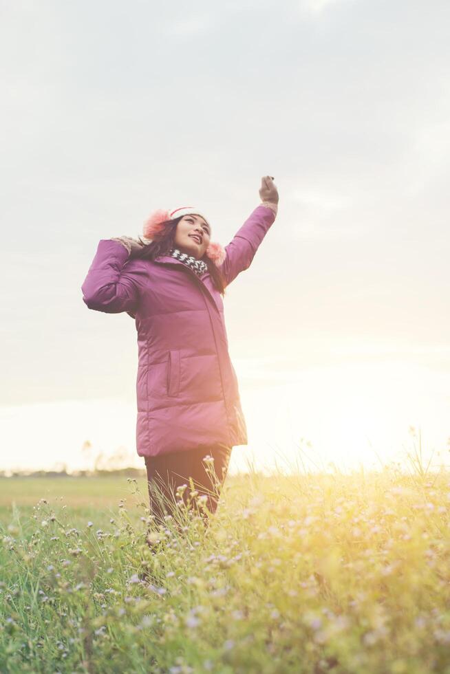 Young girl spreading hands and joy with nature while winter time at sunset background. photo