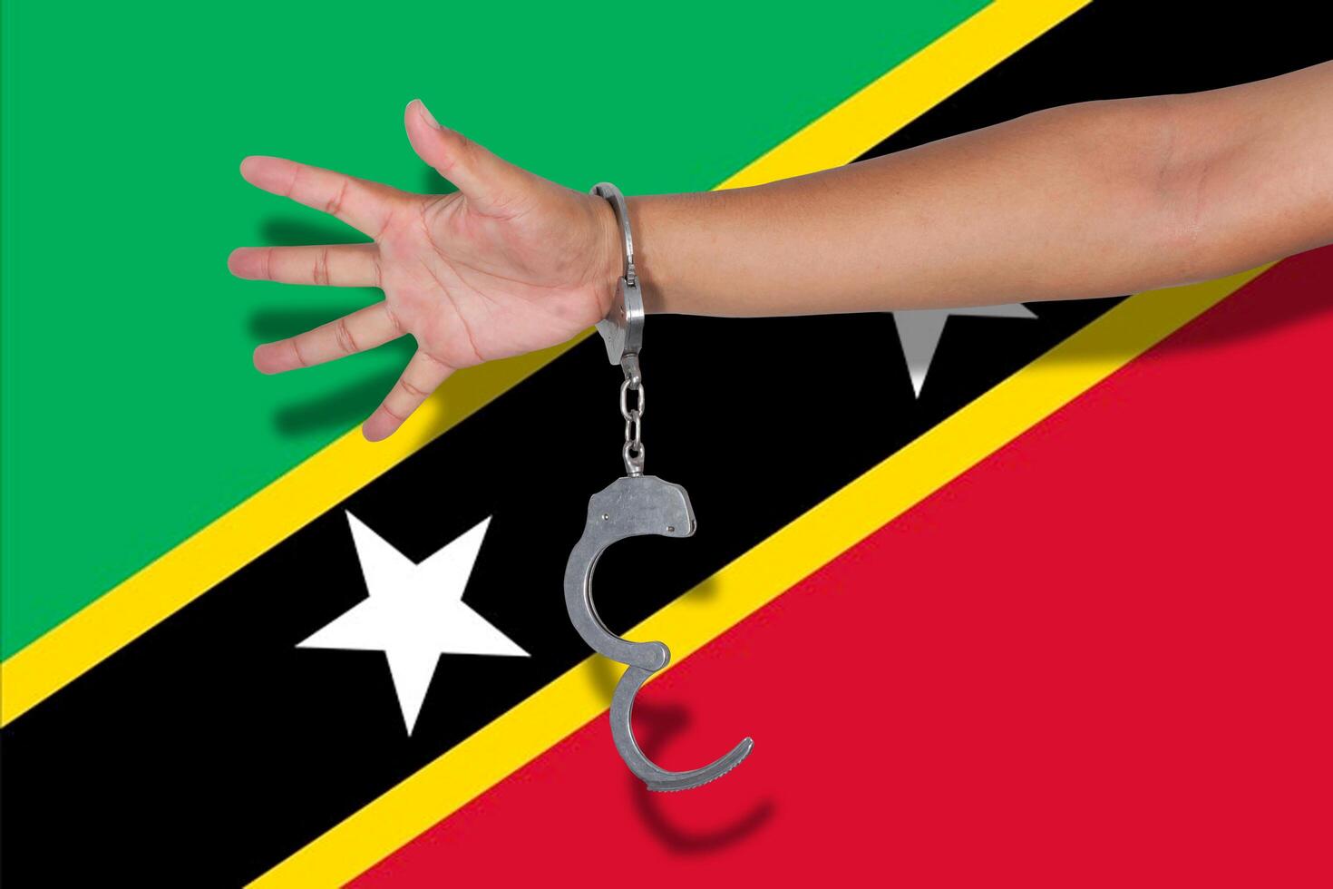 handcuffs with hand on Saint Kitts Nevis flag photo