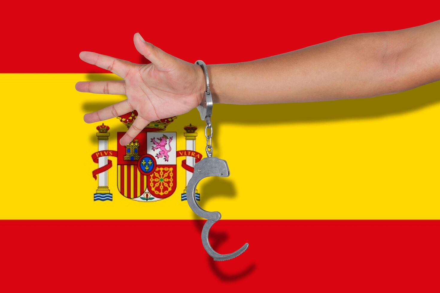 handcuffs with hand on Spain flag photo