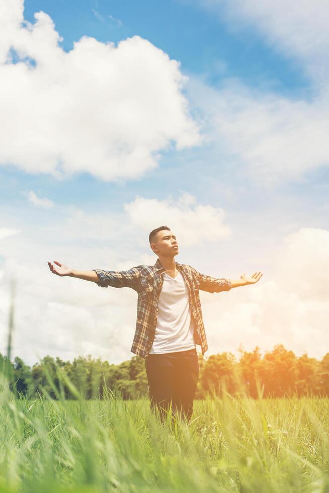 libertad joven adolescente estirando sus brazos hacia el cielo disfruta y feliz con aire fresco en los pastizales. foto