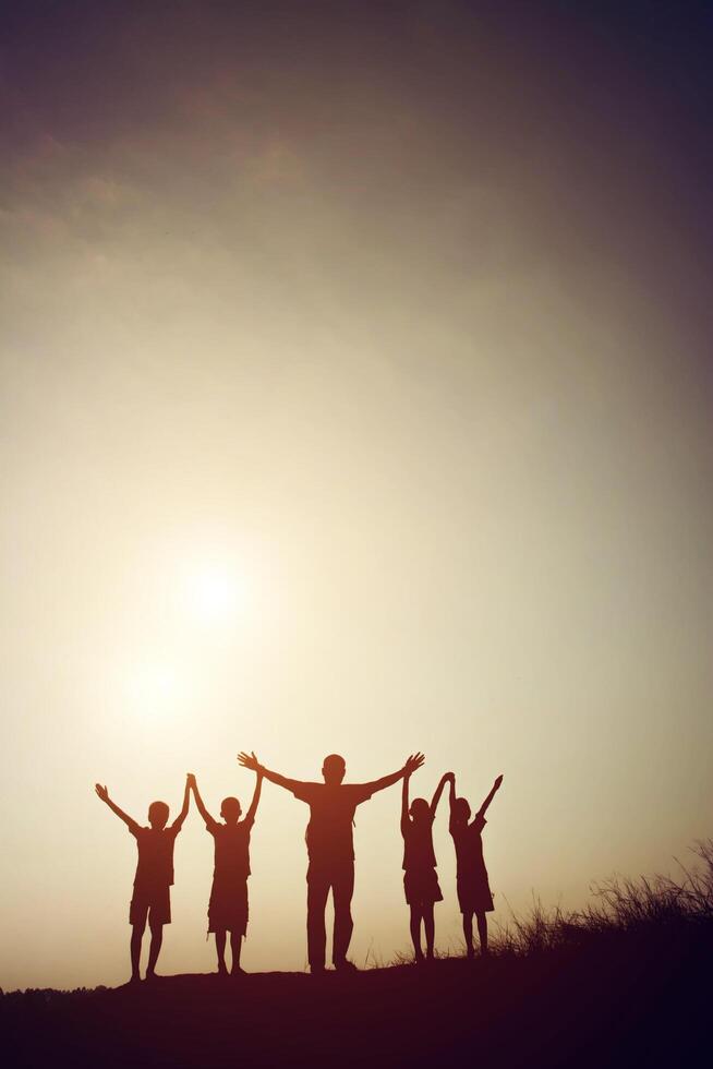 silhouette of a happy children holding hands together and happy time with sunset. photo