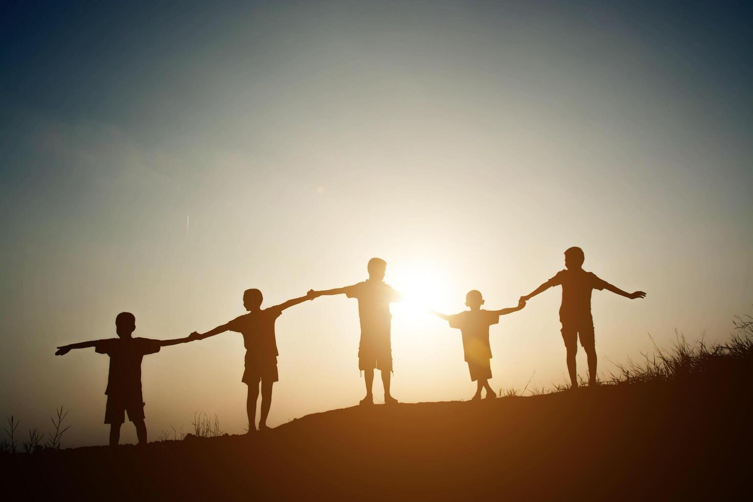 group of children silhouettes holding hands together. photo