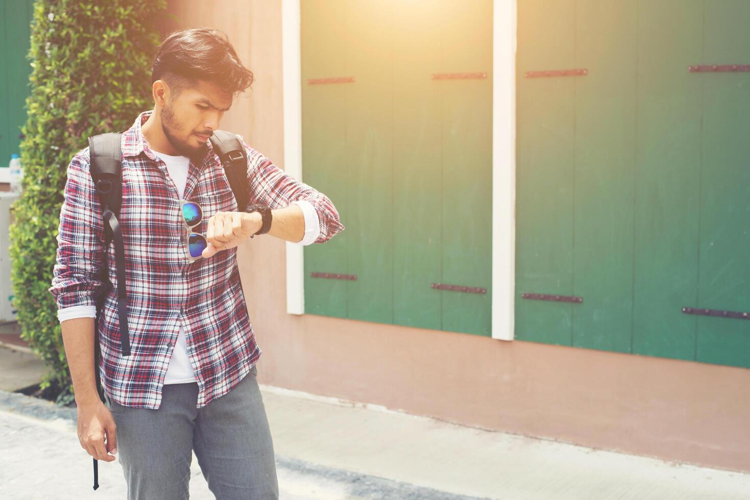 Young man looking at his hand-watch before go to travel with backpack on his shoulder. photo