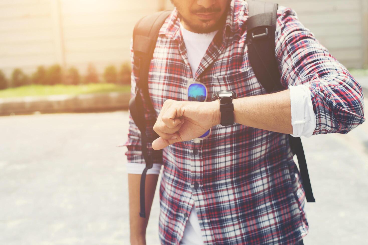 Young man looking at his hand-watch before go to travel with backpack on his shoulder. photo