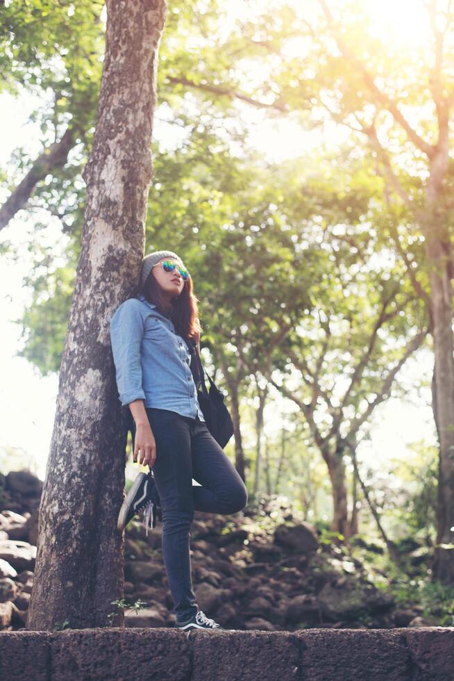 chica atractiva de pie contra el árbol, mientras viaja. foto